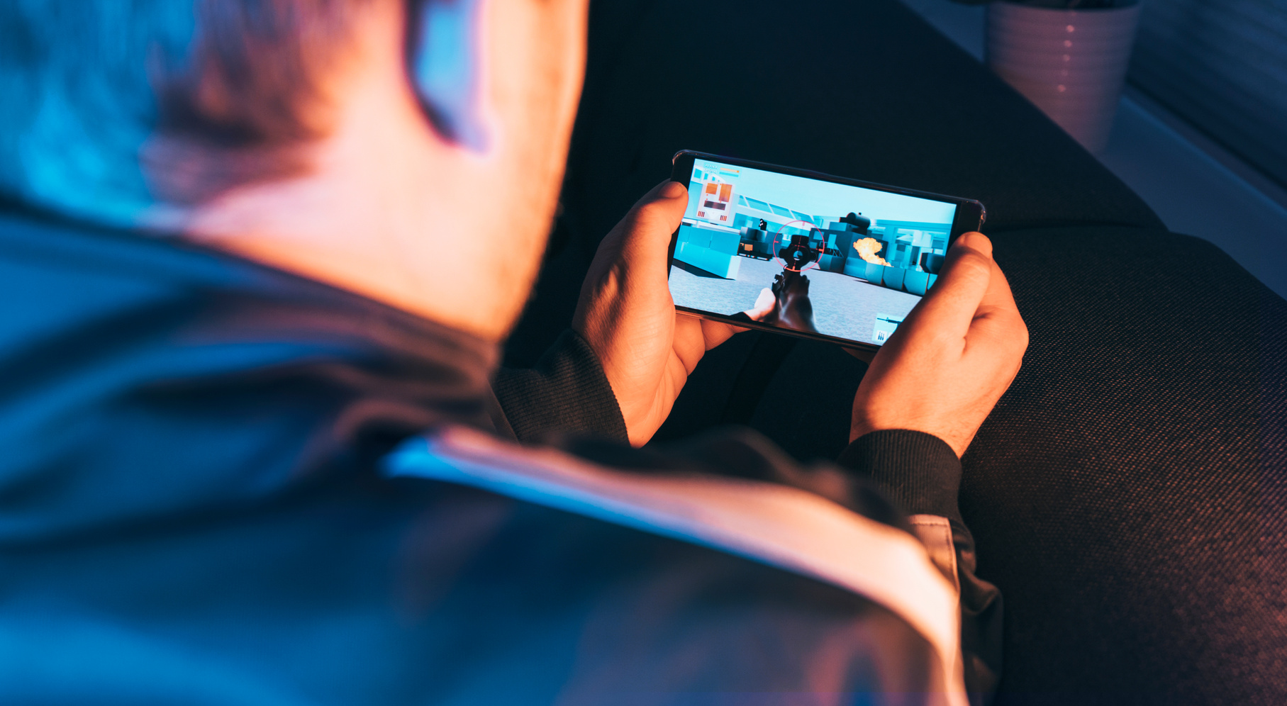 Action video game played by man holding mobile phone